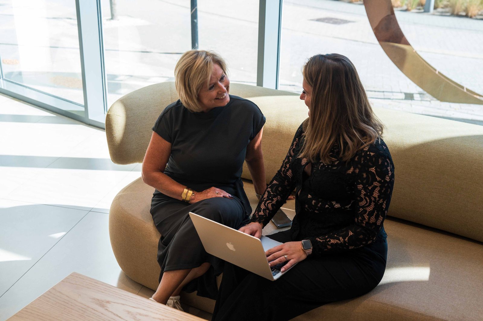 Two colleagues working on a laptop in a lounge area