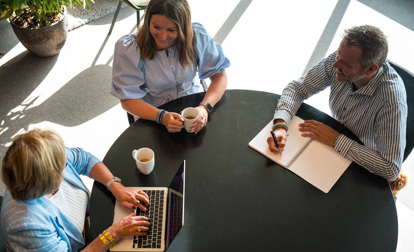 Colleagues meeting around a table with coffee and laptops